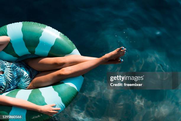 mooie vrouwen die in het zwembad ontspannen terwijl het zitten op opblaasbare ring - opblaasband stockfoto's en -beelden