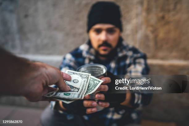 hombre sin hogar recibiendo dinero - limosna fotografías e imágenes de stock