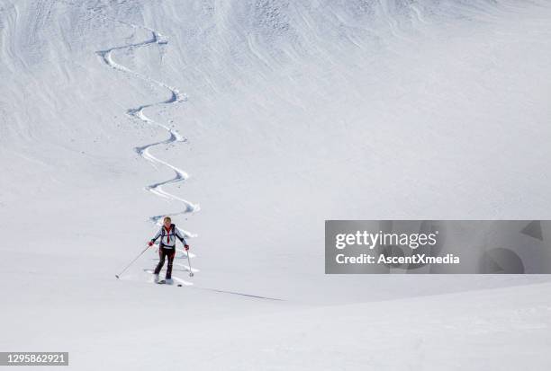 backcountry skier descends snow slope in mountains - professional skier stock pictures, royalty-free photos & images
