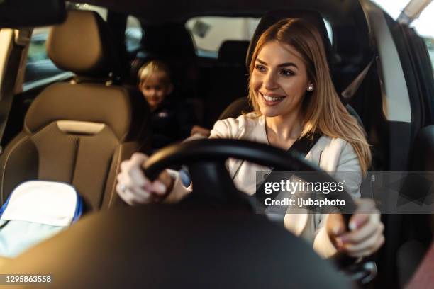 feliz madre soltera y su hijo probando coche nuevo en una sala de exposición - mujer conduciendo fotografías e imágenes de stock