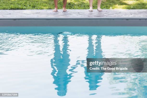 reflection of two girls standing at edge of swimming pool - reflection pool - fotografias e filmes do acervo