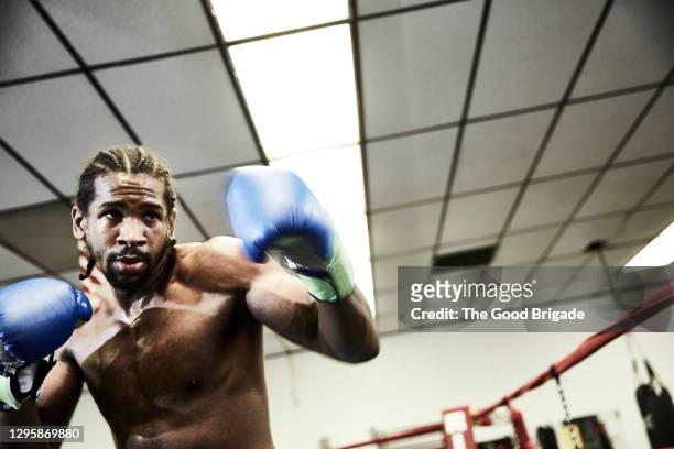 low angle view of shirtless male boxer practicing at health club - black male bodybuilders foto e immagini stock