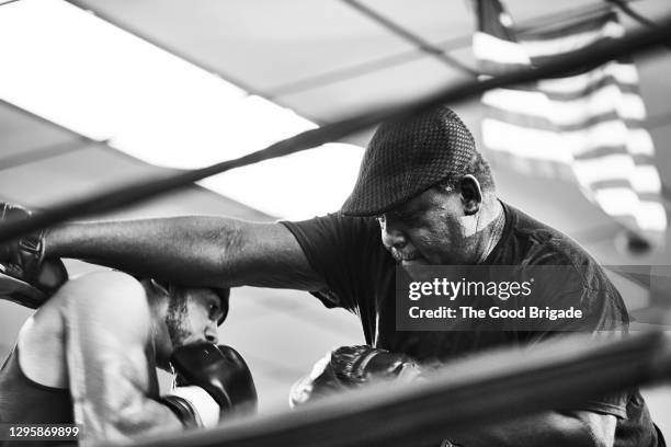 male coach teaching boxer in boxing ring at health club - extreme depth of field stock pictures, royalty-free photos & images