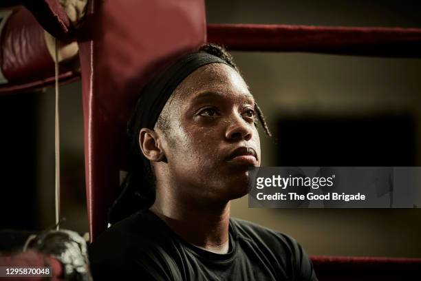 tired female boxer looking away while sitting in boxing ring - sport determination stock-fotos und bilder