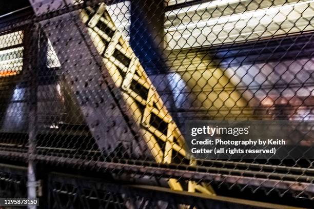 long exposure of a speeding train on a bridge behind a fence at night - bridge architecture up close night stock pictures, royalty-free photos & images