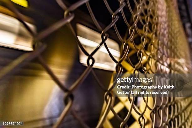 long exposure speeding train close-up behind fence at night - chain link fence stock-fotos und bilder