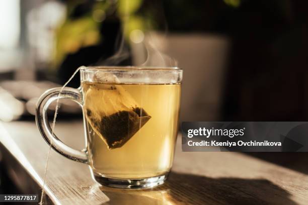 putting tea bag into glass cup full of hot water - blak and white leaves fotografías e imágenes de stock