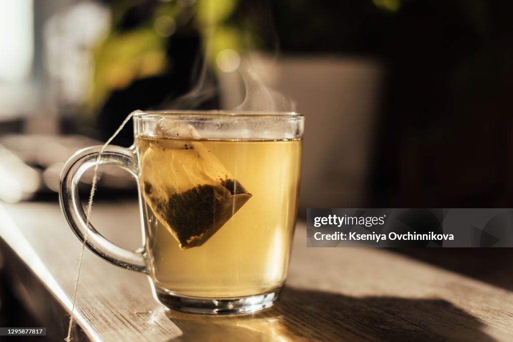 Putting tea bag into glass cup full of hot water