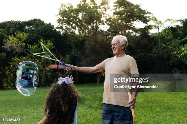 nonno che fa bolle di sapone per la nipote - big bubble foto e immagini stock