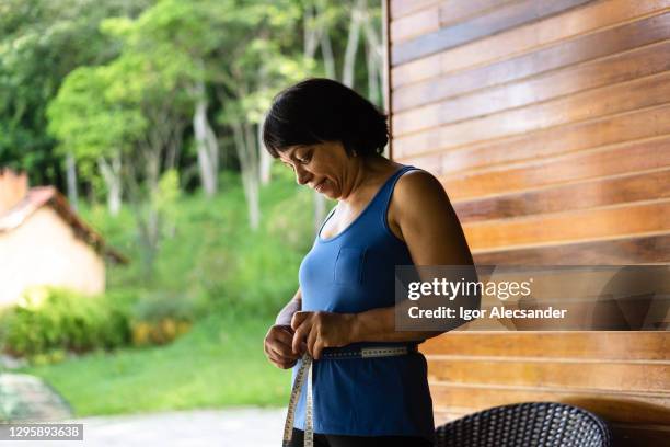 smiling woman measuring her waist - instrument of measurement stock pictures, royalty-free photos & images