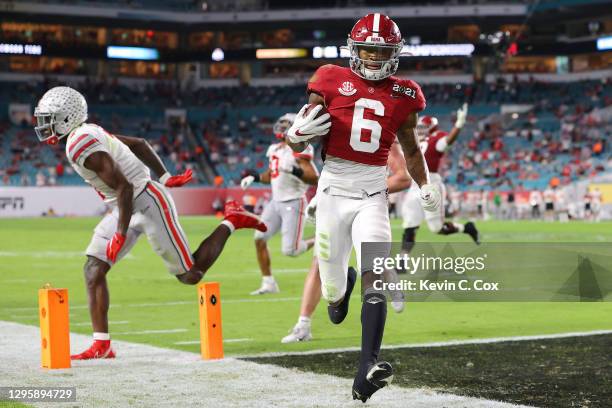DeVonta Smith of the Alabama Crimson Tide rushes for a five yard touchdown ahead of Sevyn Banks of the Ohio State Buckeyes during the second quarter...