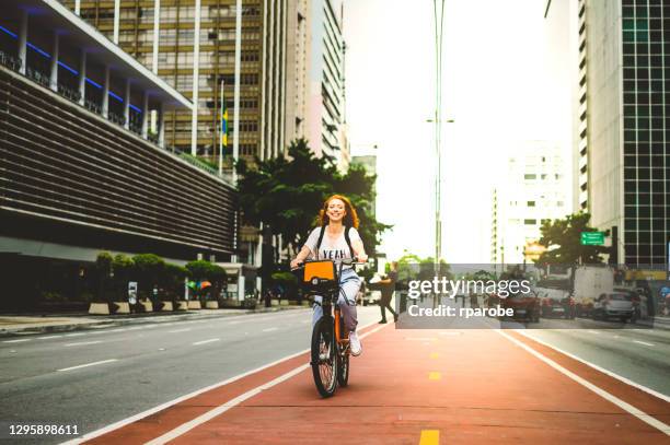 eine junge frau lächelnd, während sie fahrradfahren, paulista avenue hinunter - bike path stock-fotos und bilder