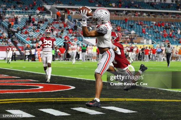 Garrett Wilson of the Ohio State Buckeyes makes a 20 yard reception for a touchdown ahead of Brian Branch of the Alabama Crimson Tide during the...