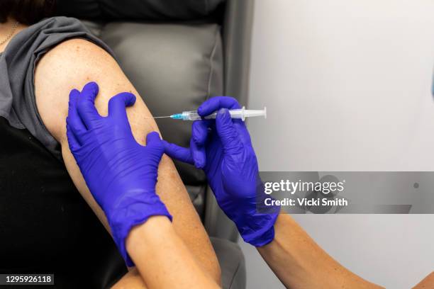 human hands in protective purple gloves injecting into a persons upper arm, medication that is in a syringe - aussie flu stock pictures, royalty-free photos & images