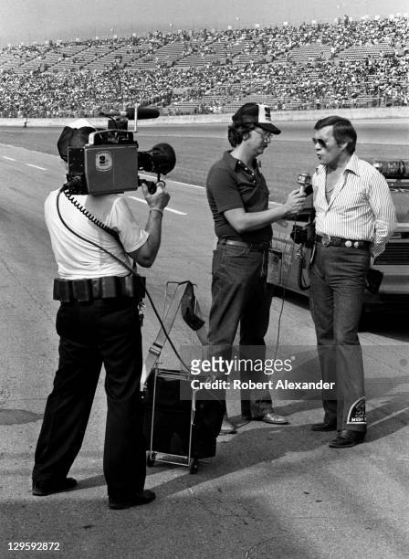 Car owner, film director and stuntman Hal Needham is interviewed by a Daytona Beach television reporter at the Daytona International Speedway prior...