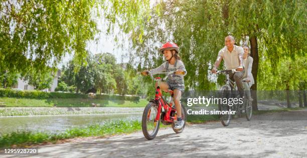 family riding bicycle - family riding bikes with helmets stock pictures, royalty-free photos & images