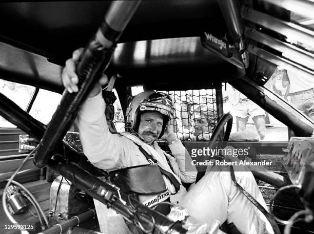 Driver Dale Earnhardt Sr. Sits in his race car while it is repaired after an accident during the 1981 Firecracker 400 on July 4, 1981 at the Daytona...