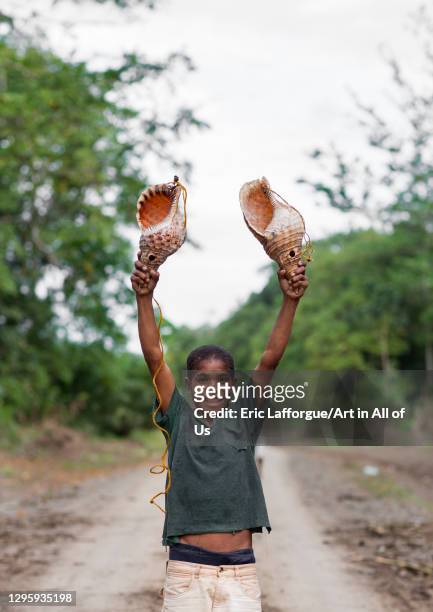 Boy holding two giant shells used to call friends, Milne Bay Province, Alotau, Papua New Guinea on October 3, 2009 in Alotau, Papua New Guinea.