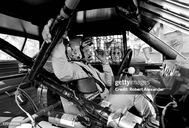 Driver Dale Earnhardt Sr. Sits in his race car while it is repaired after an accident during the 1981 Firecracker 400 on July 4, 1981 at the Daytona...