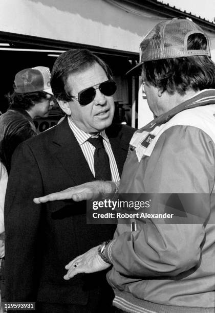 Bill France Jr., left, talks with Wrangler Jeans car owner Bud Moore in the Daytona International Speedway garage area prior to the start of the 1983...