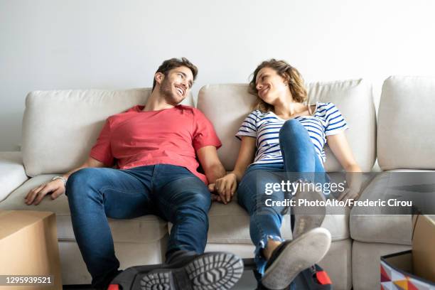 young couple relaxing on sofa in their new house - couple couch imagens e fotografias de stock