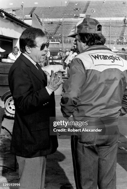 Bill France Jr., left, talks with Wrangler Jeans car owner Bud Moore in the Daytona International Speedway garage area prior to the start of the 1983...