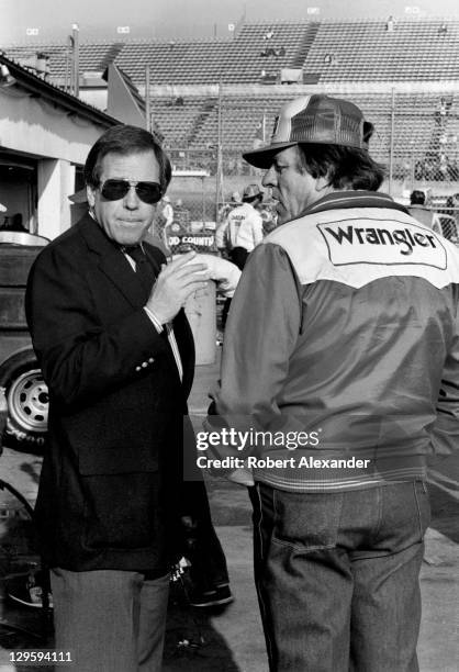 Bill France Jr., left, talks with Wrangler Jeans car owner Bud Moore in the Daytona International Speedway garage area prior to the start of the 1983...