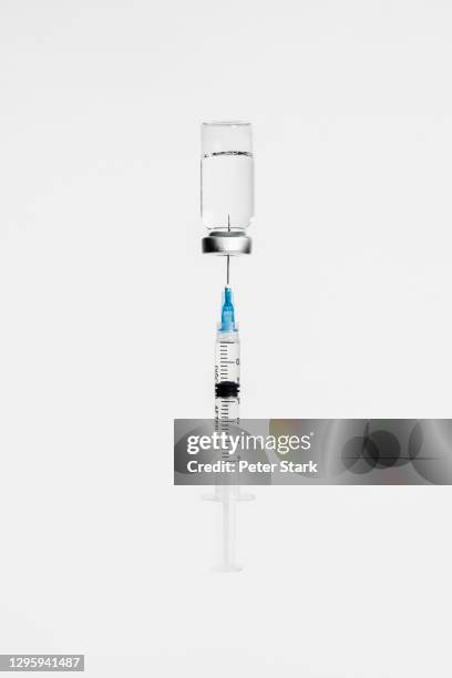 syringe in covid-19 vaccine vial on white background - medicinflaska bildbanksfoton och bilder
