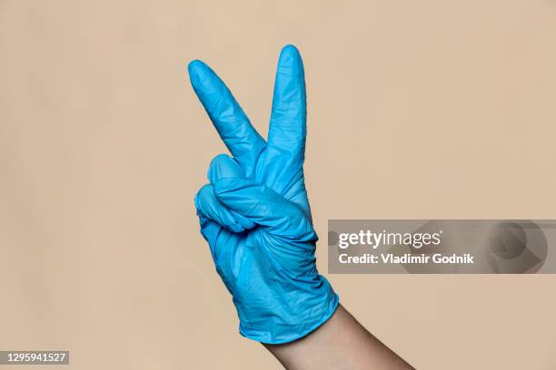 hand in protective glove gesturing peace sign - blue glove stock pictures, royalty-free photos & images