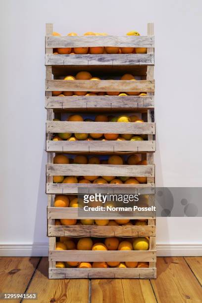 crates of fresh harvested oranges stacked against wall - crate stock pictures, royalty-free photos & images