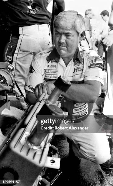 Race car owner Junior Johnson works on the engine of his No. 11 Budweiser car, driven by Darrell Waltrip, prior to qualifying for the 1985 Daytona...