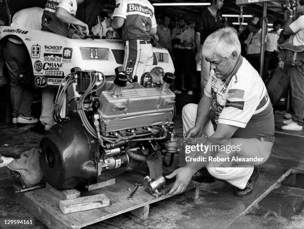 Race car owner Junior Johnson works on the engine of his No. 11 Budweiser car, driven by Darrell Waltrip, prior to qualifying for the 1985 Daytona...