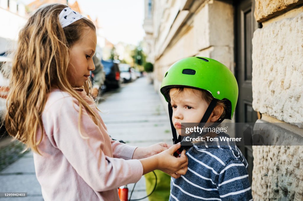 Young Girl Helping Younger Brother Fit His Bike Helmet