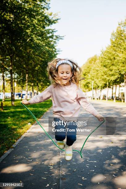 young girl in mid air using jump rope - springtouw stockfoto's en -beelden