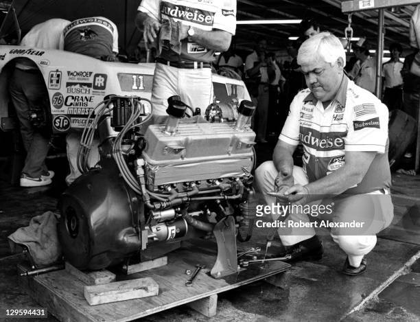 Race car owner Junior Johnson works on the engine of his No. 11 Budweiser car, driven by Darrell Waltrip, prior to qualifying for the 1985 Daytona...