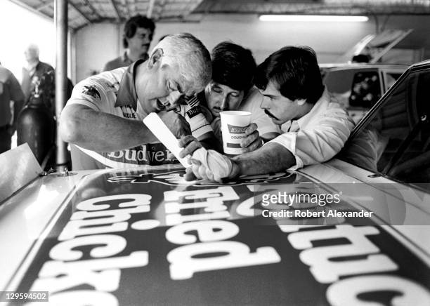 Car owner Junior Johnson, left, gives advice to his car's driver, Neil Bonnett, center, and Bonnett's crew chief, Jeff Hammond, in the Daytona...