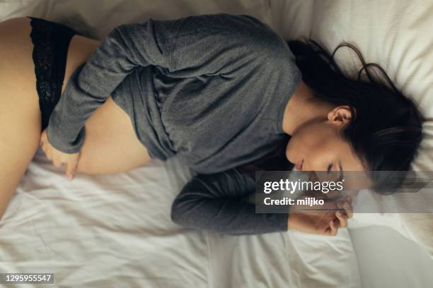 junge schwangere frau entspannt zu hause - lying on side stock-fotos und bilder