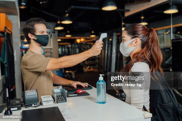 gym owner using infrared thermometer to check customer's body temperature - ladies first screening reception stock pictures, royalty-free photos & images
