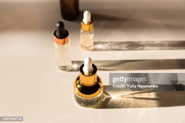 cosmetic serum bottle with a pipette in harsh light. harsh shadows. - lap body area stock-fotos und bilder