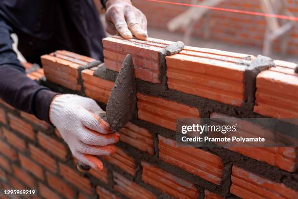 close up hand of bricklayer worker installing bricks on construction site - maçon photos et images de collection