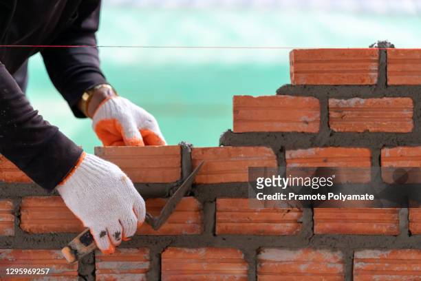 bricklayer worker installing bricks on construction site - mason bricklayer stock pictures, royalty-free photos & images