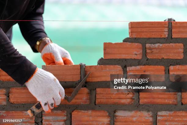 bricklayer worker installing bricks on construction site - pedreiro imagens e fotografias de stock