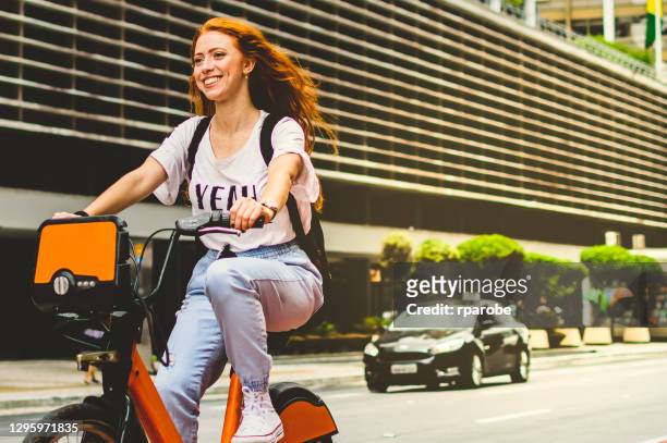 eine frau lächelnd, während sie mit dem fahrrad in séo paulo fährt - são paulo city stock-fotos und bilder