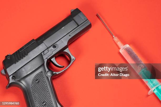 gun close to a syringe. - violence prevention stock pictures, royalty-free photos & images