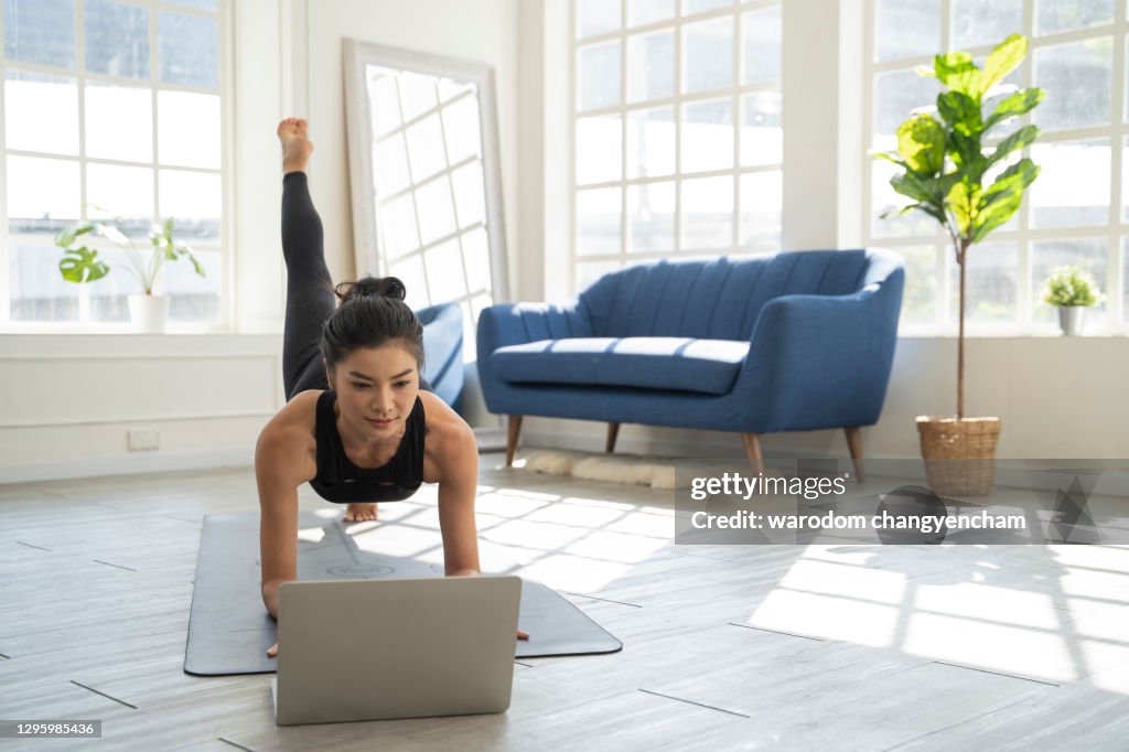 Asian woman doing yoga video in home.