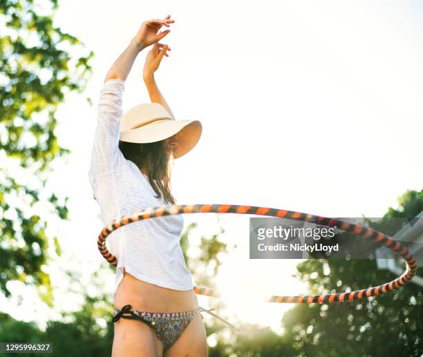 jonge vrouw die een hoelahoepel buiten in de zomer draait - waist stockfoto's en -beelden