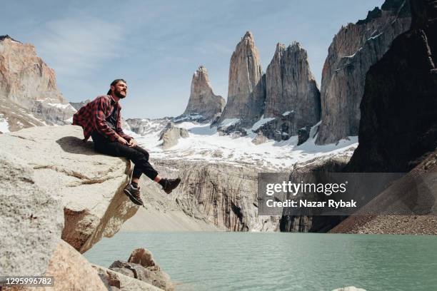 de mens zit bij toneelmening van torres del paine nationaal parkachtergrond - cuernos del paine stockfoto's en -beelden