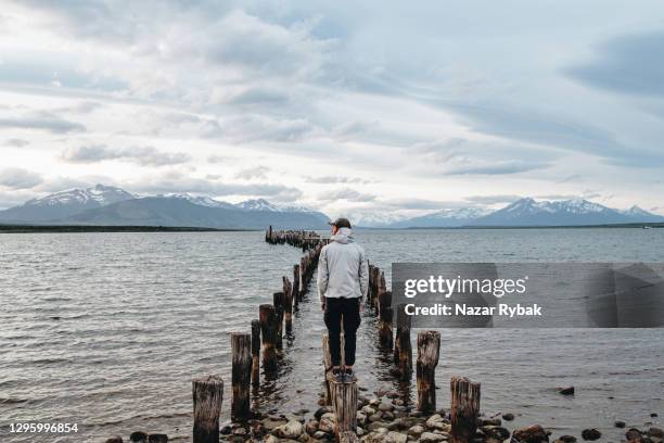 mann schaut auf alten verlassenen pier am see in patagonien - puerto natales stock-fotos und bilder