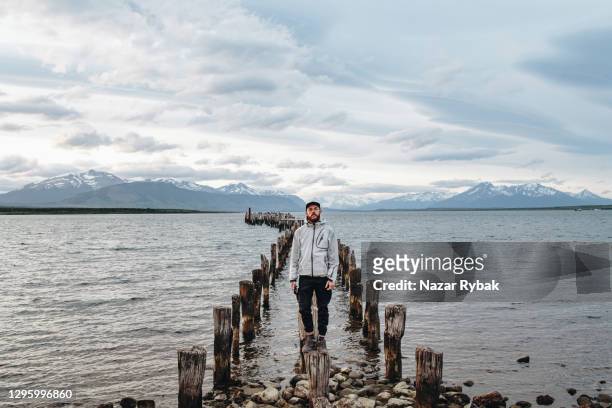 mann schaut auf alten verlassenen pier am see in patagonien - puerto natales stock-fotos und bilder