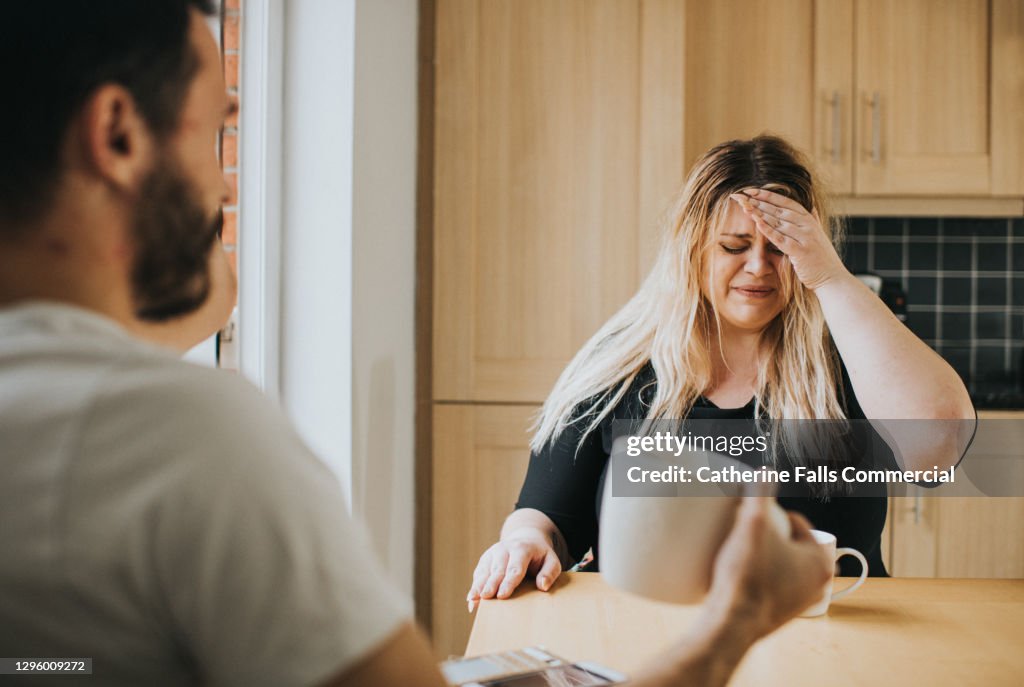 Distressed Woman at a kitchen table talking to her partner